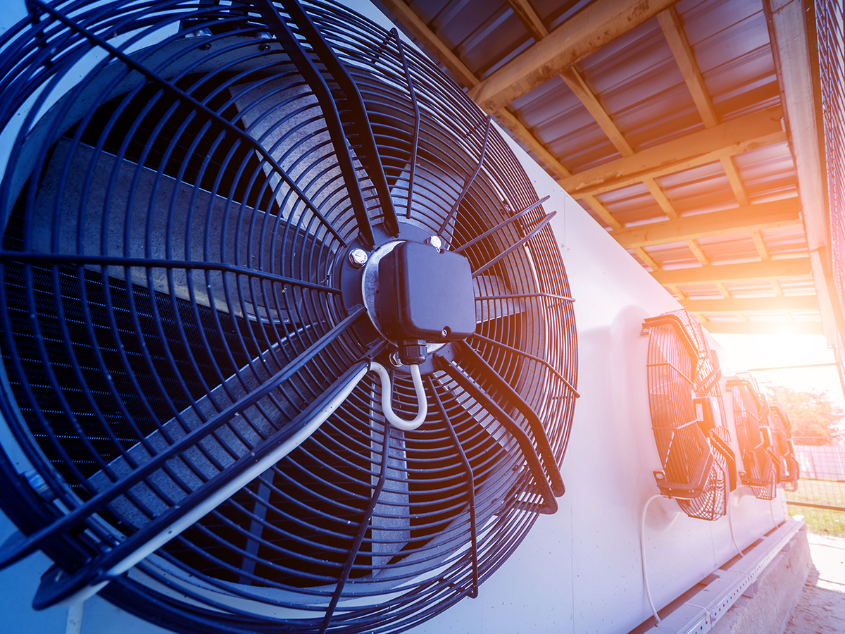 Four large industrial HVAC fans sitting with the glow of a sunset in the distance.