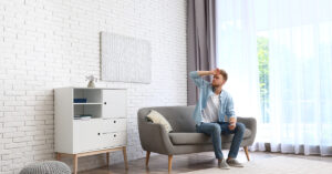 Image of a young man uncomfortably hot in his house