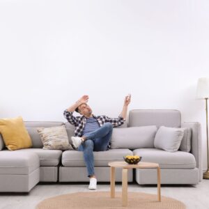 man sweating on couch wishing he had air conditioning