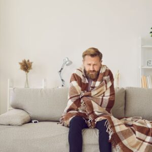 man wrapped in blanket in livingroom