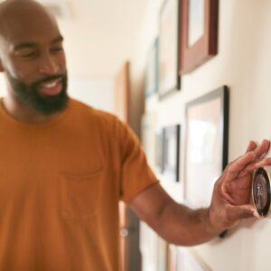 man adjusting thermostat