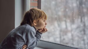 boy looking out snowy window