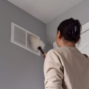 woman dusting an air vent