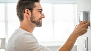 man adjusting thermostat